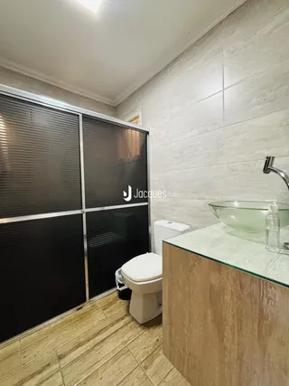 Foto de um banheiro com piso de cerâmica e bancada de vidro.