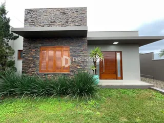 Fachada de uma casa moderna com revestimento de pedra e jardim na frente.