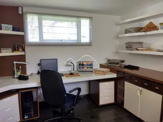 Foto de um escritório com mesa de trabalho e estantes na sala.