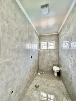 Interior de um banheiro com revestimento em cerâmica cinza.