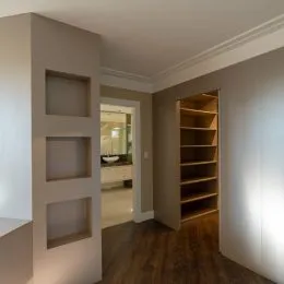 Hall de entrada com nichos em parede e piso de madeira.