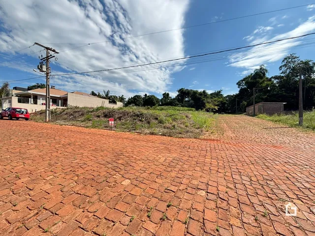 Vista externa de uma propriedade com área de pavimentação de tijolos e vegetação.