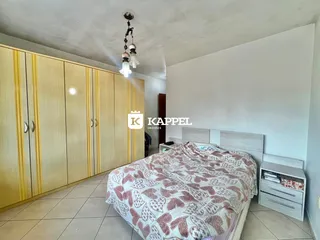 Quarto com cama e armários de madeira em um ambiente claro.