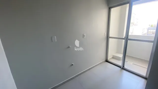Vista interna de um ambiente com paredes brancas e piso claro.