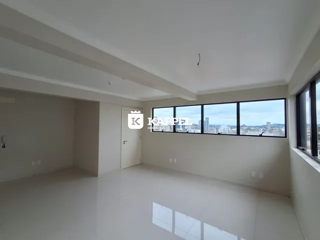 Sala ampla com piso claro e grande janela com vista da cidade.