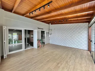 Sala de estar com piso de madeira e teto de madeira em um imóvel no Brasil.