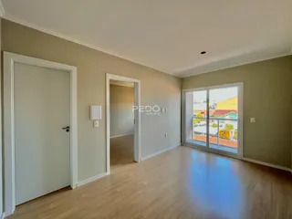 Interior de uma sala com piso de madeira e porta de entrada.