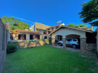 Vista externa de uma propriedade com gramado verde e estrutura de alvenaria.