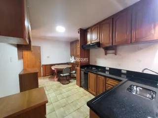 Uma cozinha e sala de jantar com armários de madeira e piso de cerâmica.