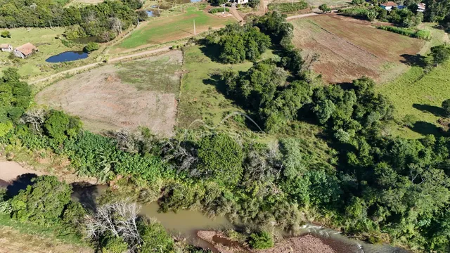 Vista aérea de uma propriedade rural com campos e vegetação densa.