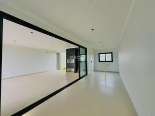 Interior de uma sala ampla com paredes brancas e piso claro.