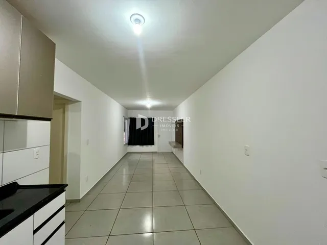 Corredor interno de uma residência com piso de cerâmica clara.