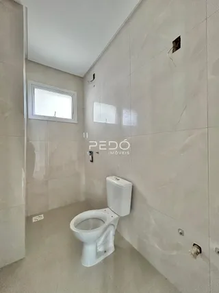 Foto de um banheiro com revestimento cerâmico claro.