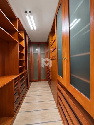 Corredor interno com revestimento de madeira e estantes.
