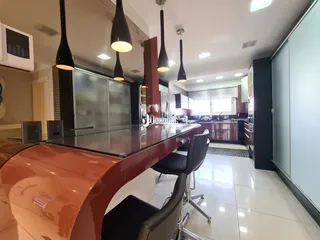 Uma cozinha moderna com ilha grande e armários escuros.