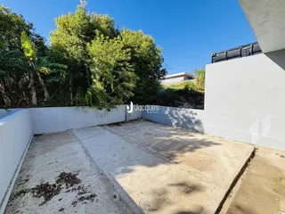 Vista de uma área externa de concreto com vegetação ao fundo.