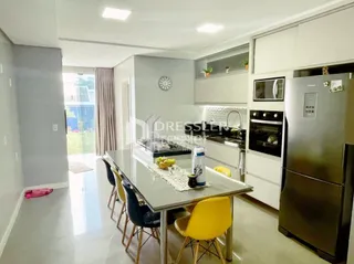 Ambiente interno de uma sala de estar com cozinha integrada e área de jantar.