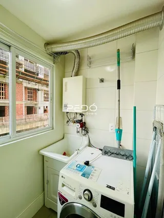 Foto de uma área de serviço com máquina de lavar roupa e pia.