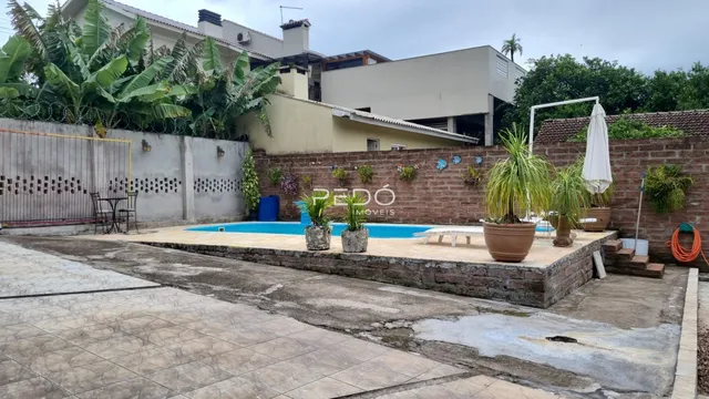 Vista externa de uma propriedade com piscina e muro de tijolos.