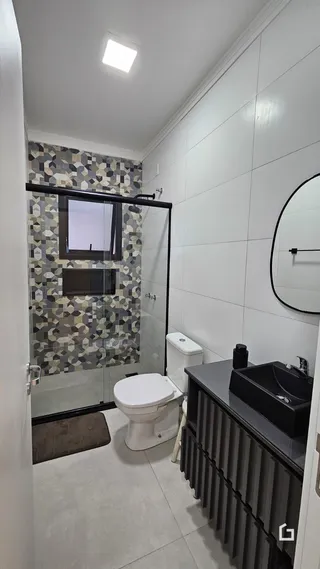 Foto de um banheiro com revestimento de azulejos geométricos e box de vidro.