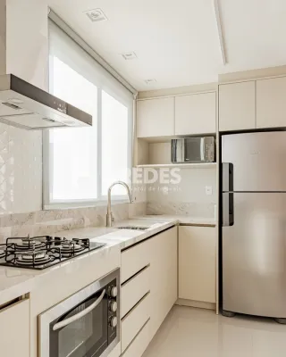 Cozinha moderna com armários brancos e bancada clara.