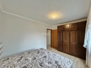 A foto mostra um quarto com cama e armário de madeira.