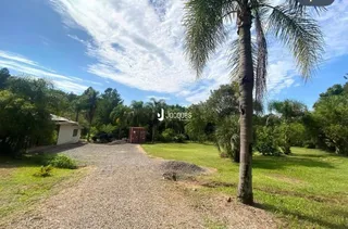 Vista da entrada da propriedade com caminho de cascalho e gramado.