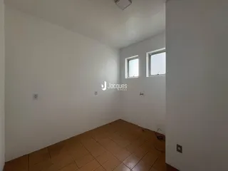 Interior de um cômodo com paredes brancas e piso de cerâmica marrom.