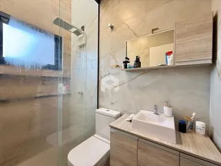 Banheiro com box de vidro e bancada de madeira em Lajeado.