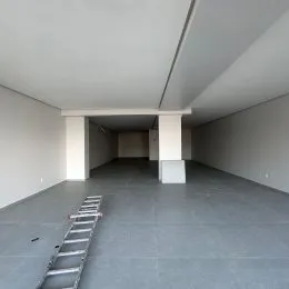 Corredor interno com paredes brancas e piso cinza.