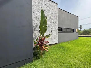 Fachada de uma residência com parede de pedra e gramado verde.