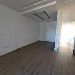 Foto de um corredor interno com piso de madeira.