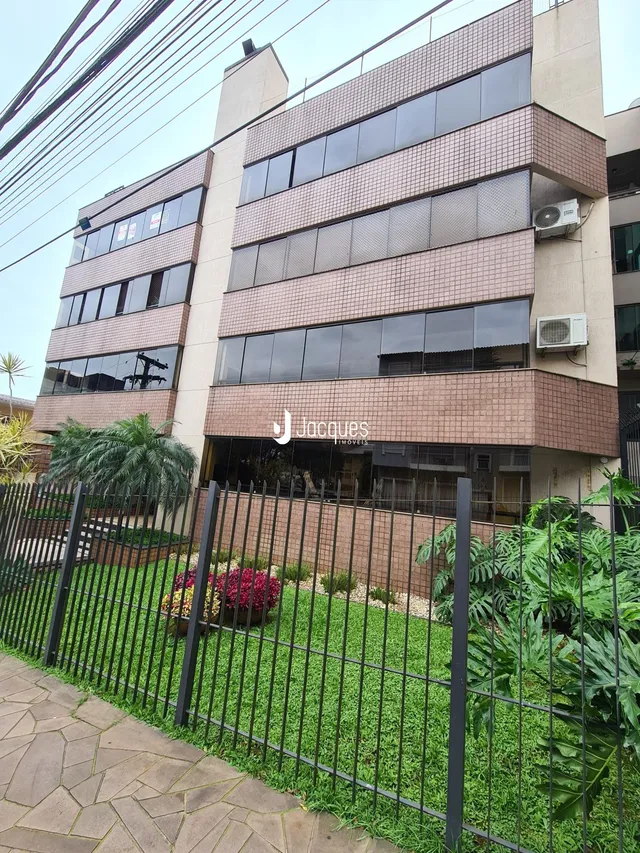Fachada de um prédio residencial com jardim e cerca em Lajeado.
