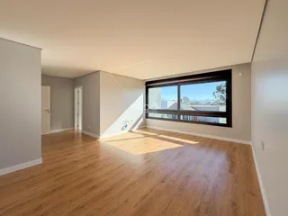 Sala de estar com piso de madeira clara e grande janela.
