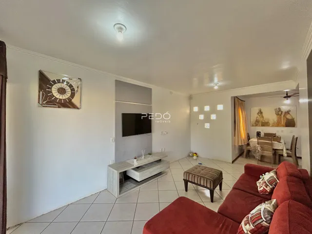 Sala de estar com sofá vermelho e piso de cerâmica em imóvel em Lajeado.