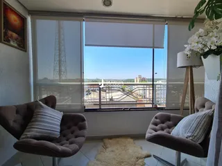 Sala de estar com grandes janelas que oferecem uma vista da cidade.