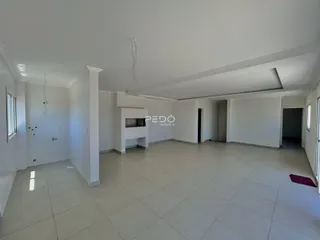 Sala ampla com piso de cerâmica e paredes brancas.