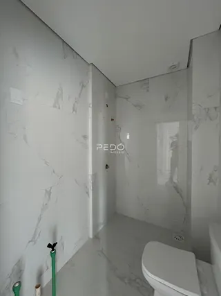 Foto do interior de um banheiro com revestimento de mármore branco.