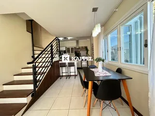 Uma sala de estar com escadaria e área de jantar em um apartamento.