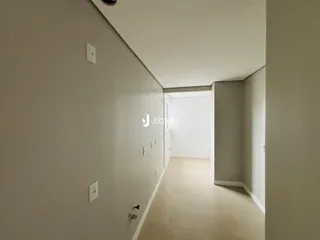 Corredor interno de uma residência com paredes claras e piso claro.