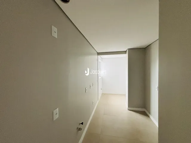 Corredor interno de uma residência com paredes claras e piso claro.