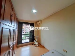 Interior de um quarto com armários de madeira e uma bicicleta ergométrica, com vista para uma área externa.