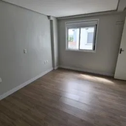 Foto de um cômodo interno com piso de madeira e janela.