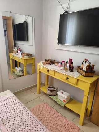 Sala de estar com móveis amarelos e televisão na parede.