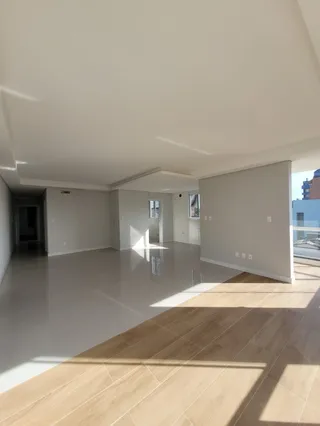 Interior de um ambiente amplo com piso de madeira clara e iluminação natural.
