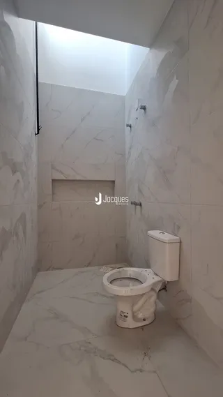 Banheiro com revestimento em mármore branco nas paredes e piso.