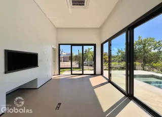Vista interna de uma sala com grandes portas de vidro que dão acesso a uma área externa.