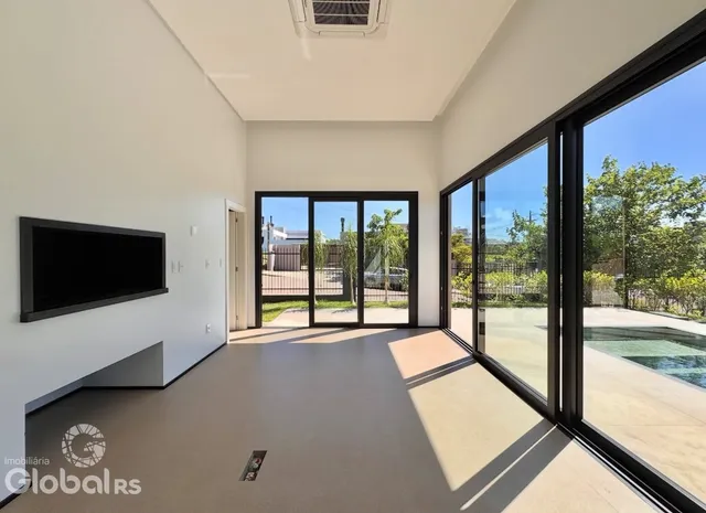 Vista interna de uma sala com grandes portas de vidro que dão acesso a uma área externa.