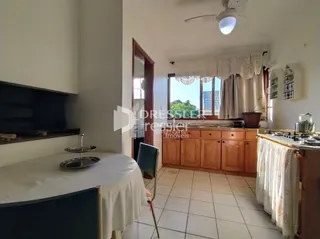 Interior de uma sala com piso de cerâmica e janela com cortinas brancas.