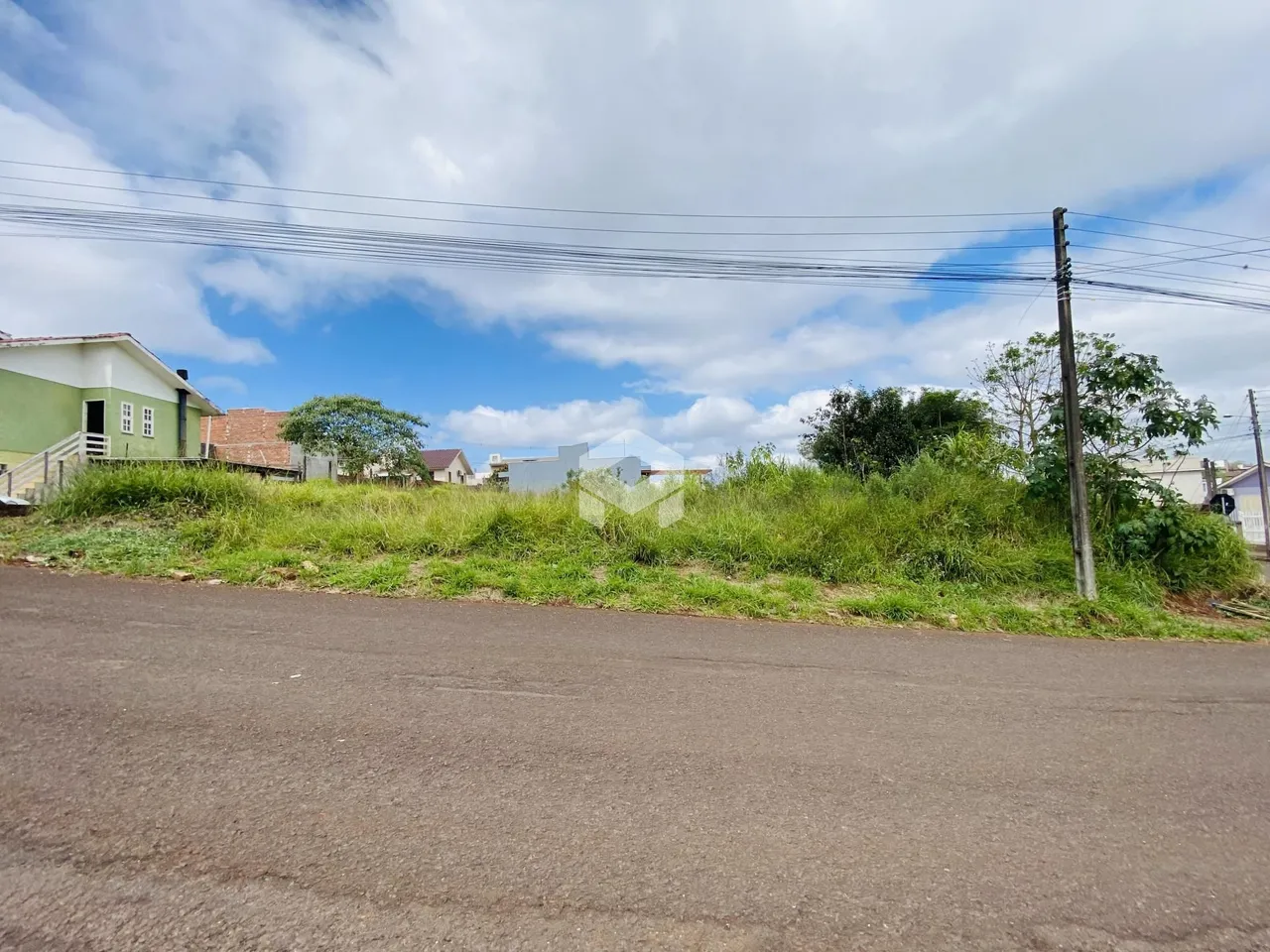 Vista da propriedade ao longo da estrada com vegetação e postes de luz.